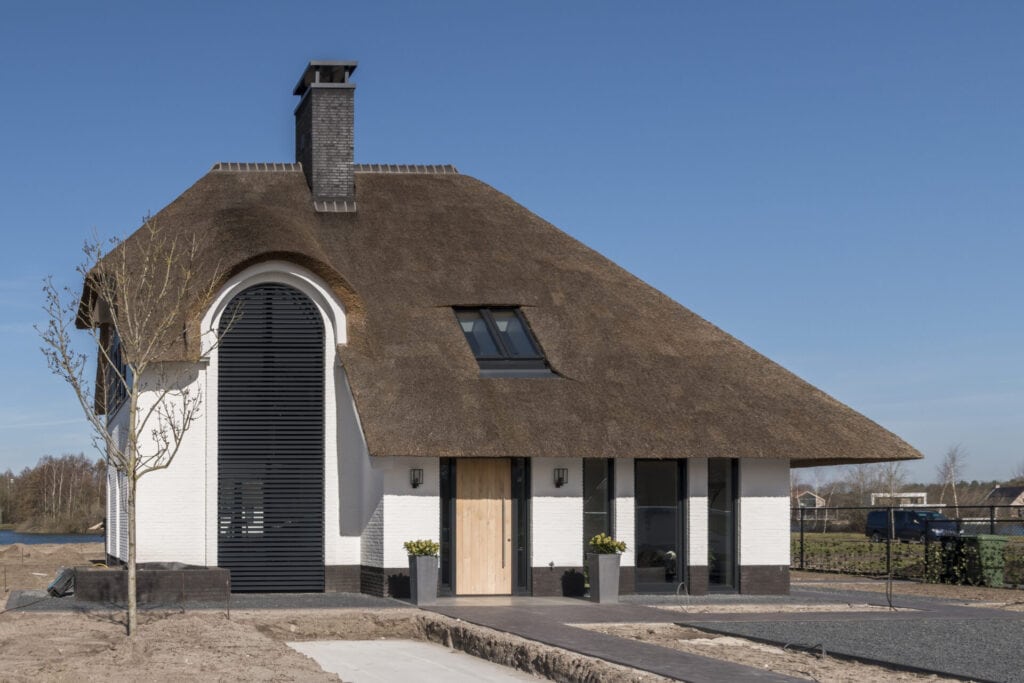 Landelijke villa met strodak met lamellen in groot boograam