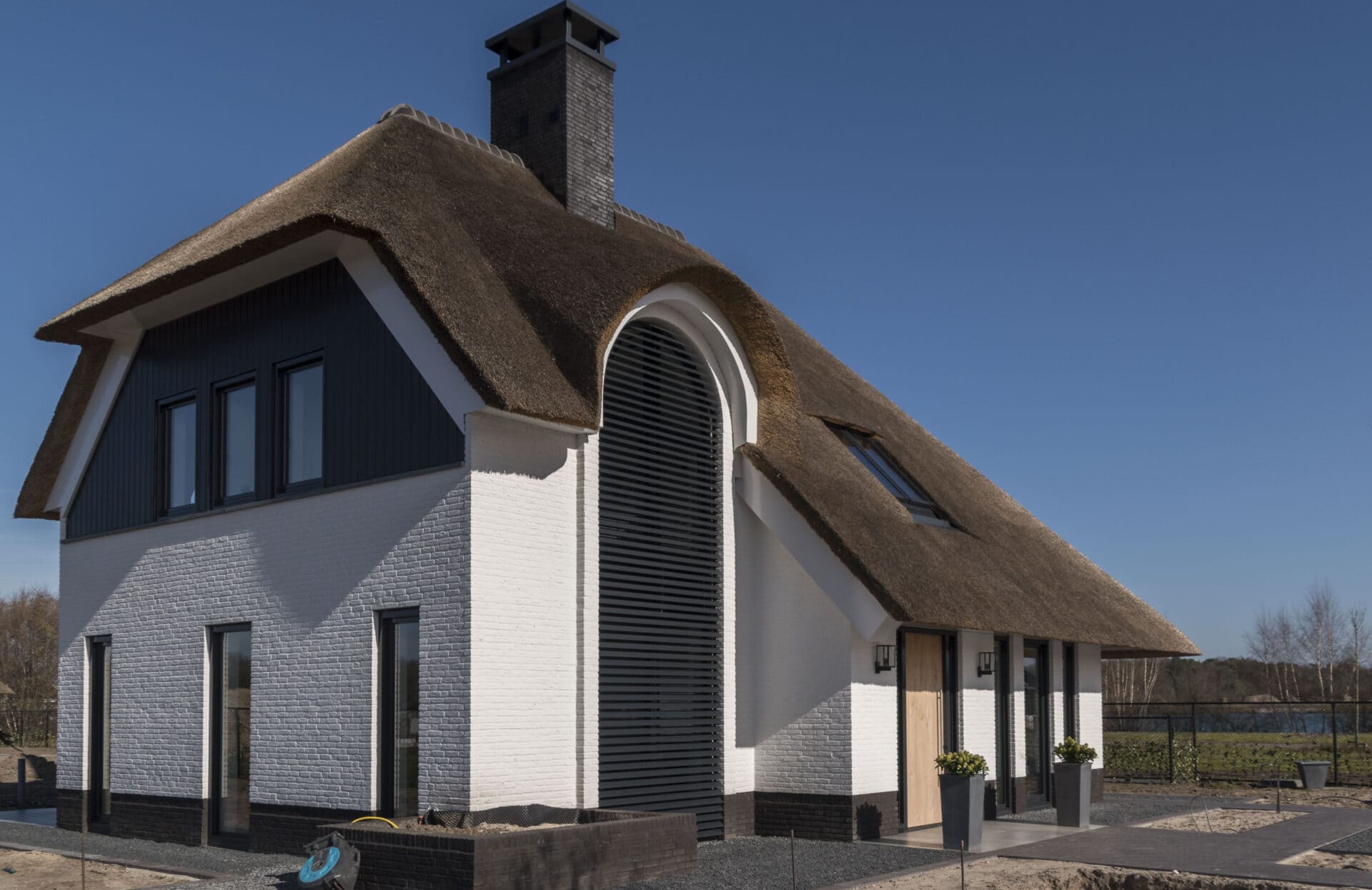 Landelijke villa met strodak met lamellen in een groot boograam