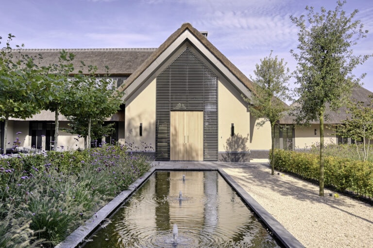 Landelijke villa met kantelbare lamellen in een puntraam om en rond de voordeur