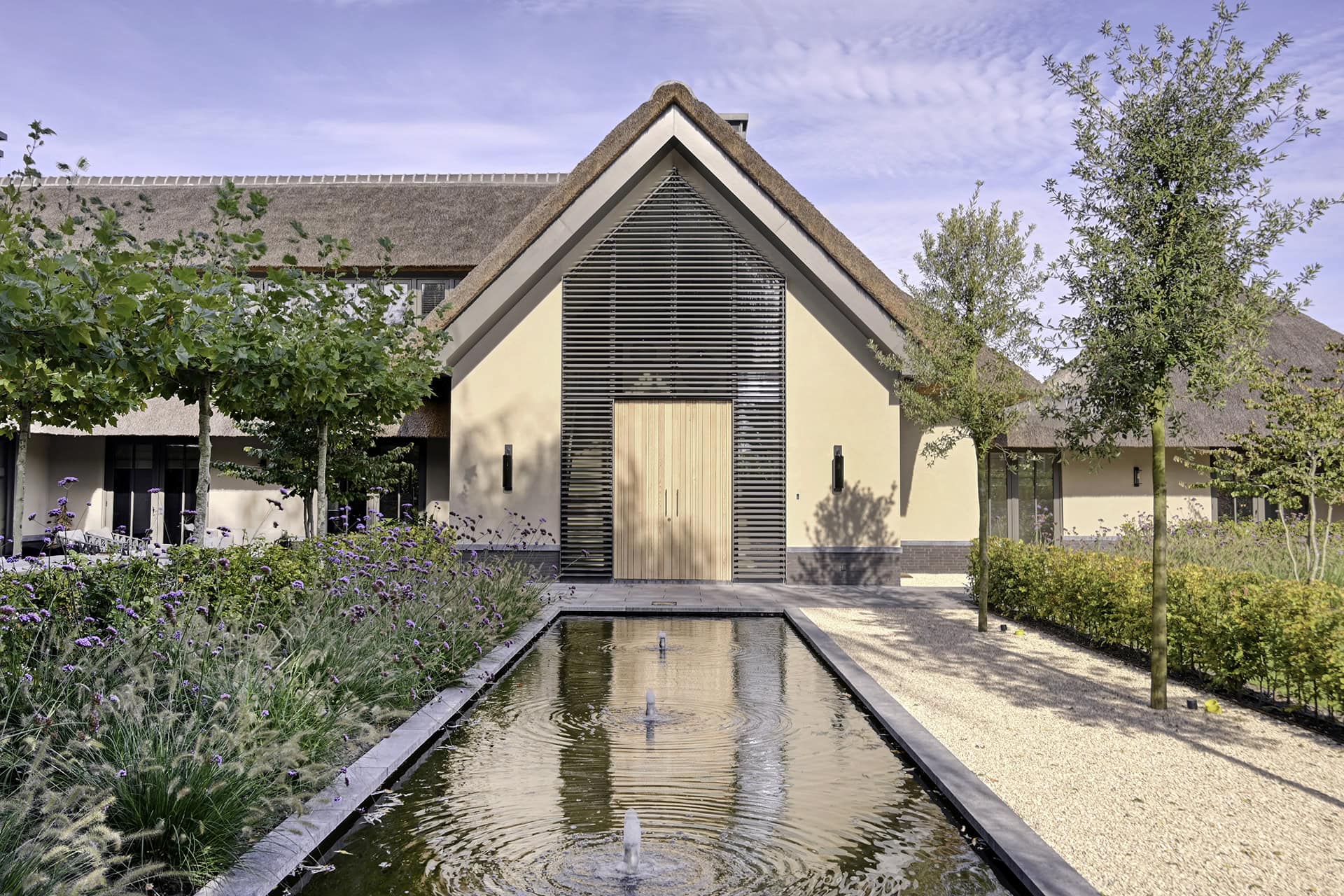 Landelijke villa met kantelbare lamellen in een puntraam om en rond de voordeur