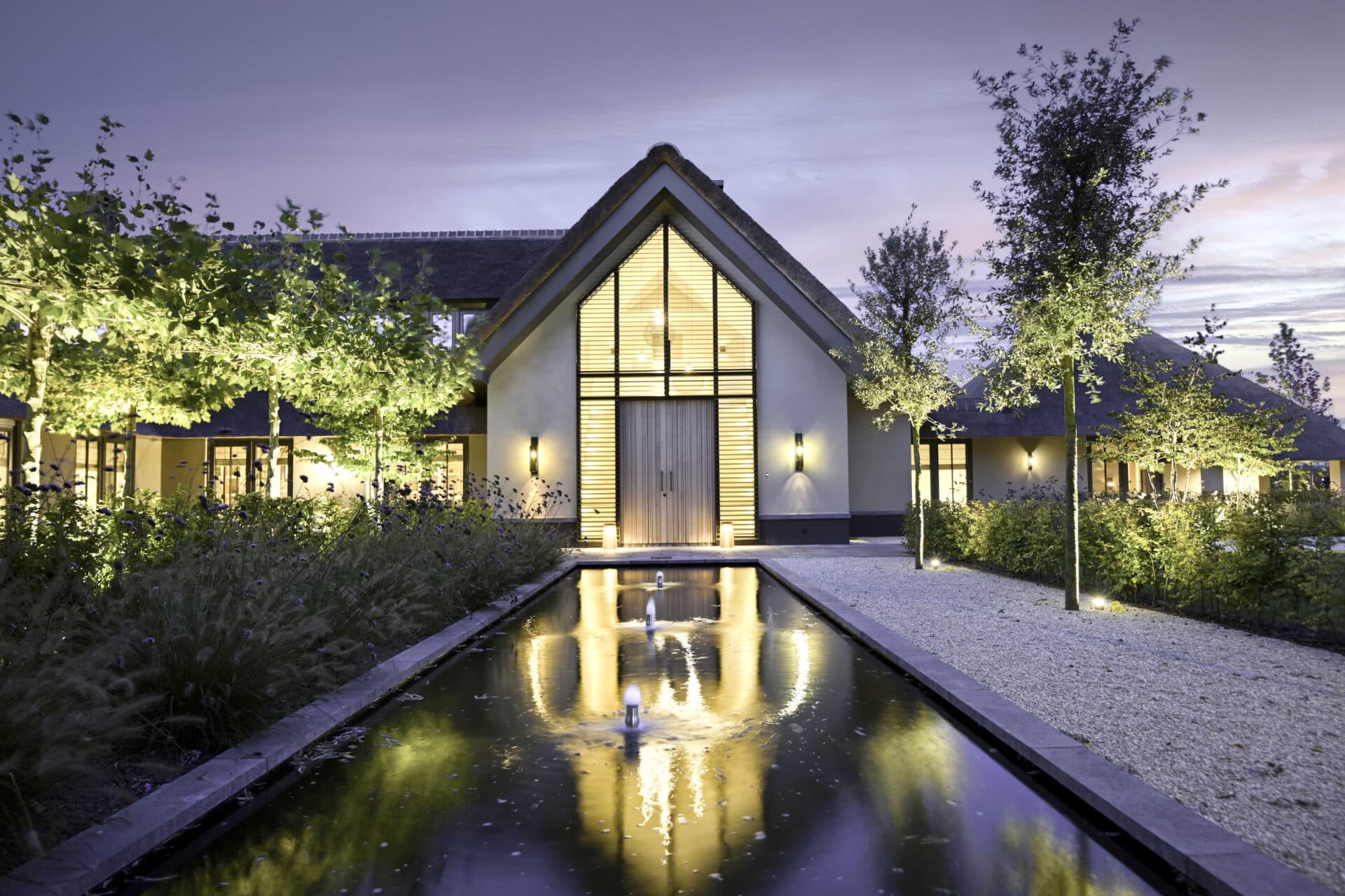 Landelijke villa in de nacht met kantelbare lamellen tot in de nok om en rond de voordeur