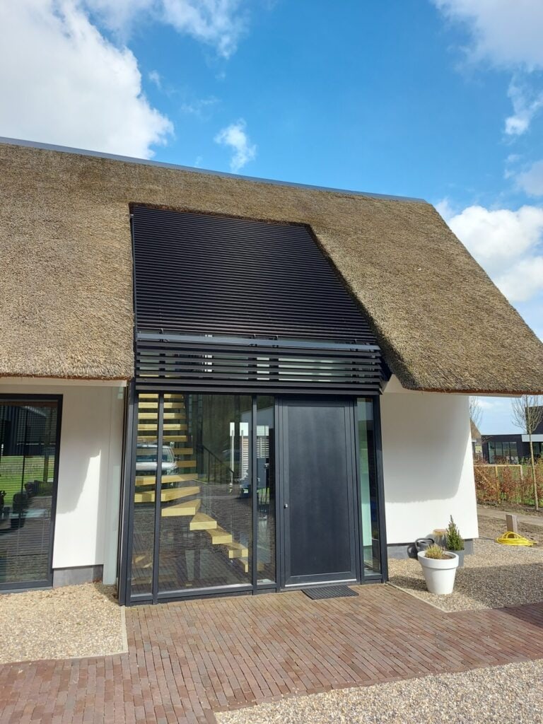 Villa met strodak waarin een glasdak in verwerkt zit. Het glasdak is voorzien van kantelbare lamellen