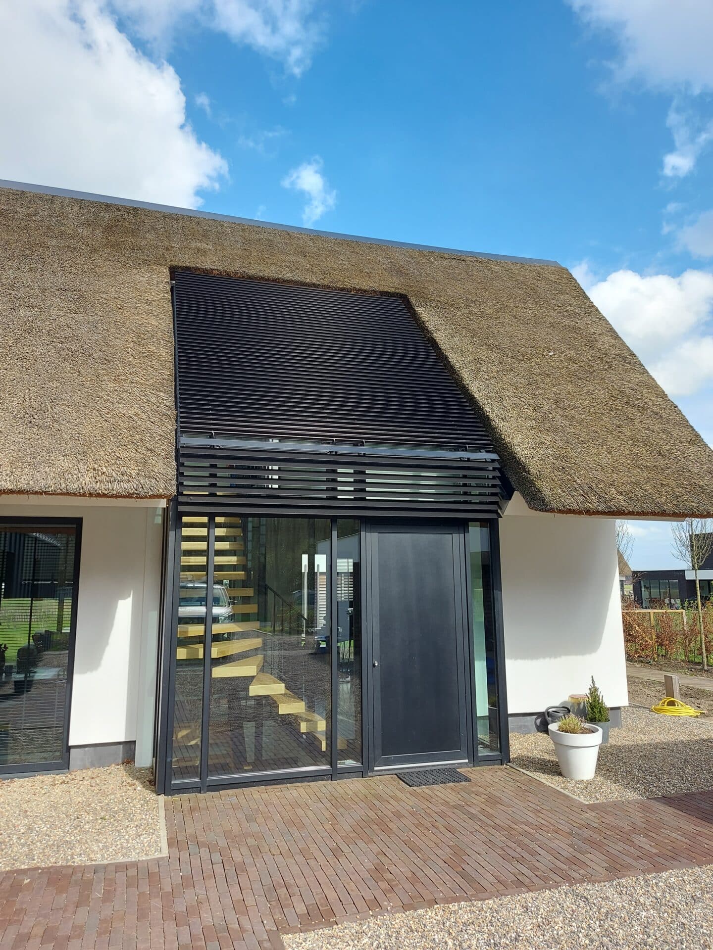 Villa met strodak waarin een glasdak in verwerkt zit. Het glasdak is voorzien van kantelbare lamellen