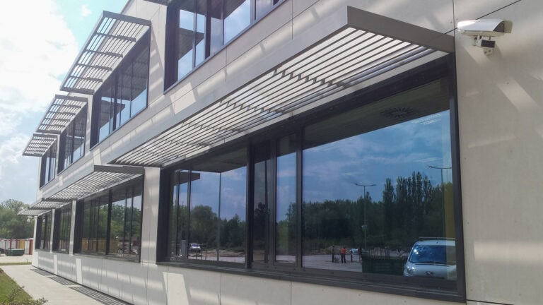 Meerdere ramen van modern kantoorgebouw uitgerust met brise soleil lamellen met de C100 louver